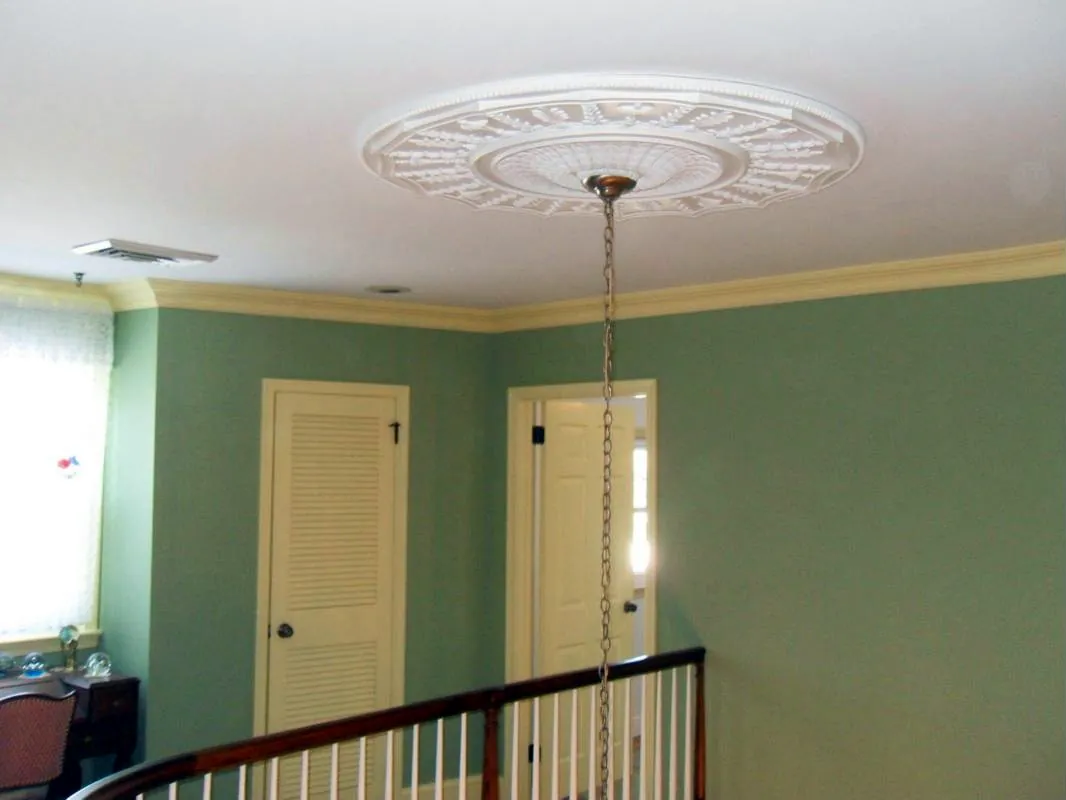 Ceiling medallion and crown molding above a painted stair hall