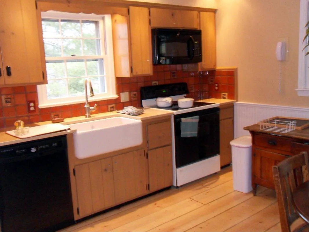 Farmhouse kitchen with apron sink, tile backsplash, beadboard wainscot and pine floors