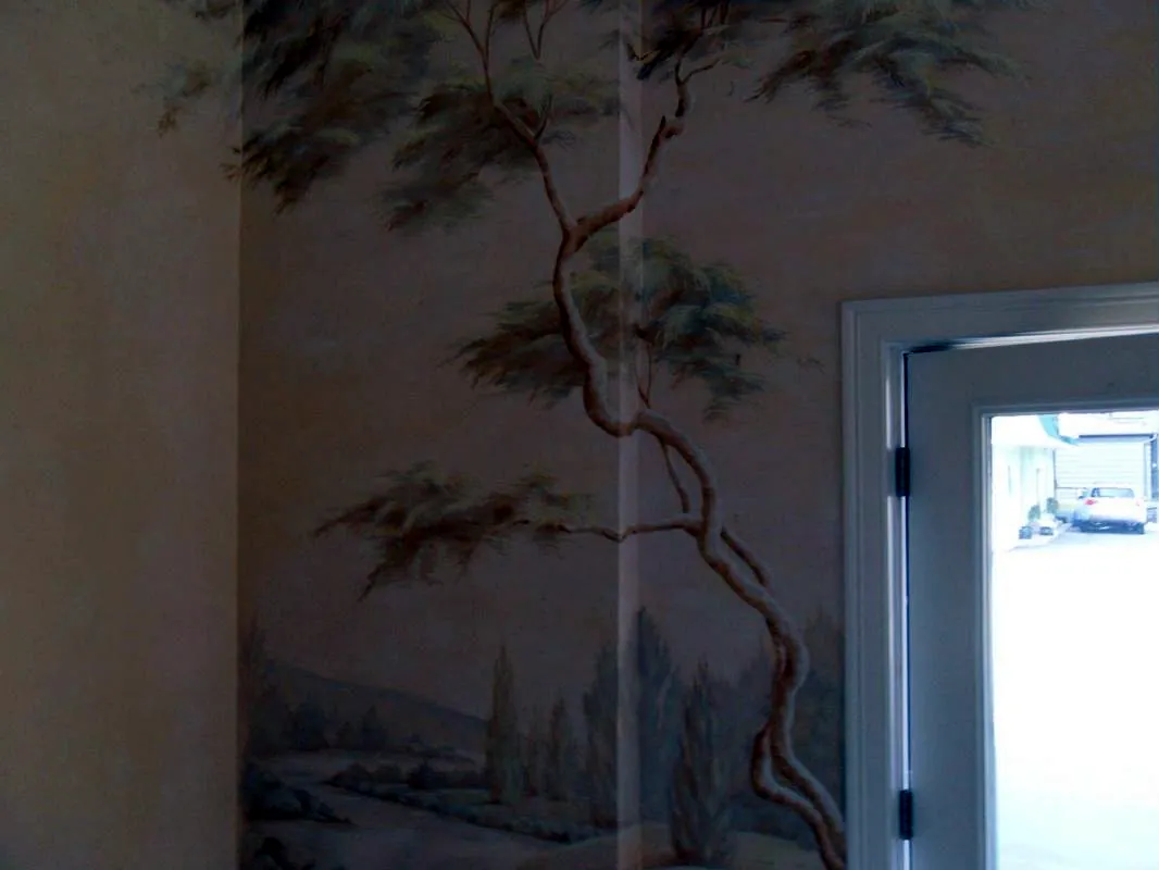 Hand-painted tree and landscape mural wrapping a corner