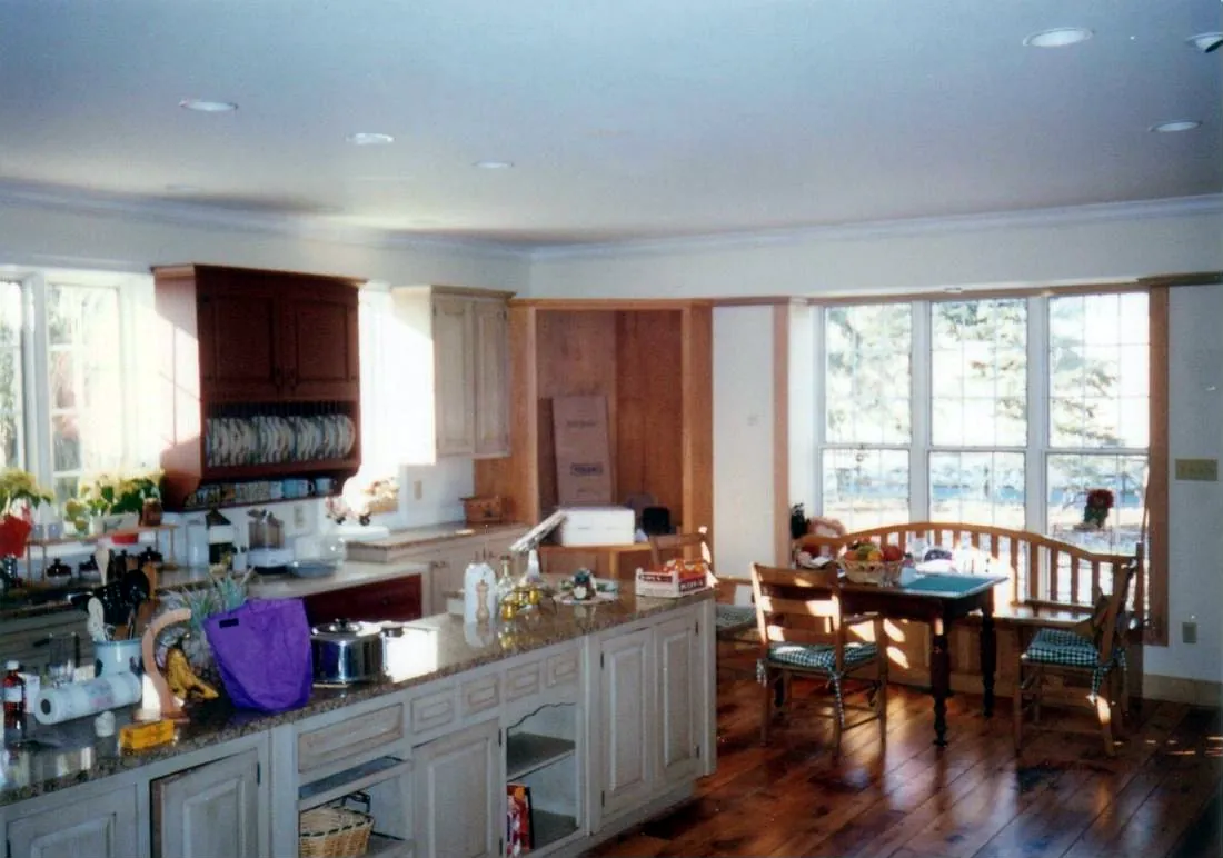Open kitchen with wide-plank wood floors, crown molding and a painted island