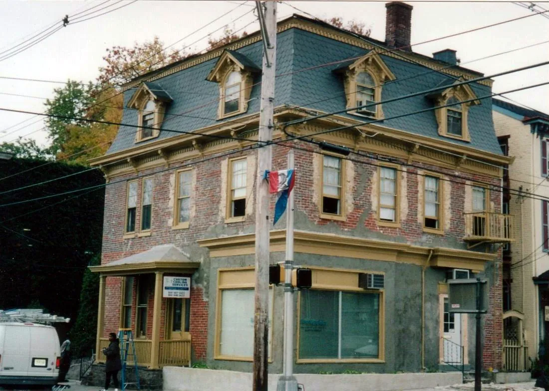 Mansard-roof brick building mid-restoration with new trim on the dormers and storefront